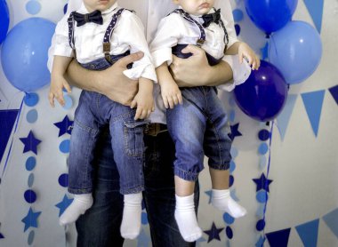 İlk doğum günlerinde, sonbahar dekorunda beyaz elbiseli ikiz kardeşler.