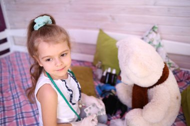 Karantinaya alınmış eğlence. Kafkasyalı tatlı küçük kız evde büyük bir kutup ayısıyla gülüp oynuyor. Koronavirüs 2019-ncov 'a karşı karantina koruması. Ev yalıtımı.