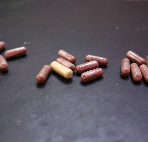 Food supplement capsules, dietary supplement, vitamin pill, herbal medicine on black background. Close-up