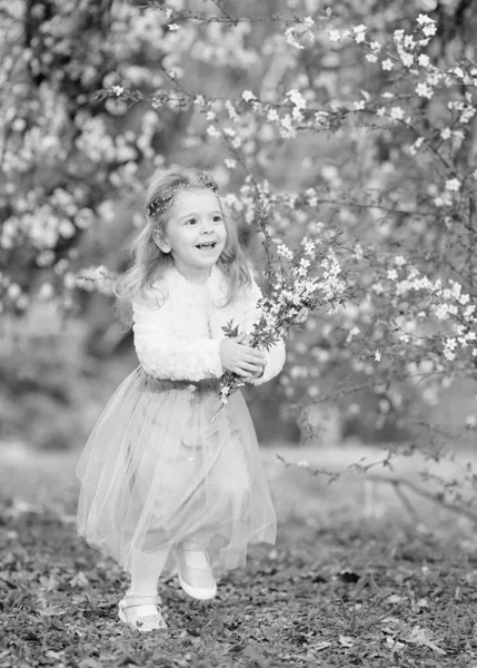 迷人的黑白肖像画小女孩笑着 穿着飘飘欲仙的裙子和毛绒衫 在春天的花园里开着一束盛开的樱花 玩得很开心 女儿的日子 复活节 — 图库照片