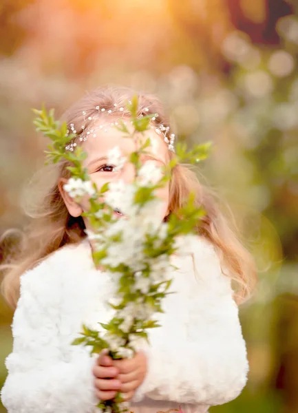 かわいい女の子が笑い 春の植物園で桜の花の花束と飛んでヌードスカートと白い毛皮のブラウスで楽しみを持っています イースターと春のカード — ストック写真