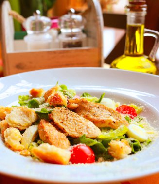 Kavrulmuş salata, bıldırcın yumurtası, kiraz domatesleri ve restorandaki bir masada beyaz tabakta ızgara tavuk.