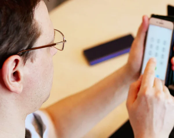 Work at home online during a pandemic 2019-ncov. Serious young man in glasses calls on a mobile phone at work sitting at his workplace. Close-up. Online Job Concept. Self-isolation