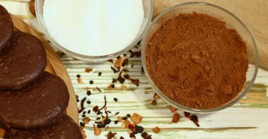 Orjinal Nuremberg zencefilli kurabiye ve ahşap desenli beyaz bir arka plan içerikli sahne. Kakao, şeker, süt. Üst Manzara. Sağlıklı bir kahvaltı için gerekli malzemeler. Kahve dükkanı reklam konsepti