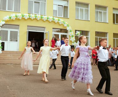Ukrayna Kiev Mayıs 2019. İlkokul mezunları. Güzel çocuklar açık okul bahçesinde dans ediyorlar. Aileler ve öğretmenler için düzenlenen son çan festivalinde. Modern okul ve eğitim kavramı