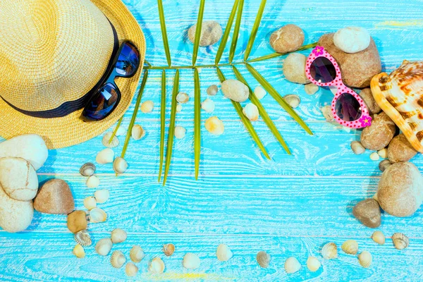 banner with beach accessories on a blue board aquamarine color background. Hat, sunglasses, sea shells, sea stones. Travel and tourism. Summer vacation concept.