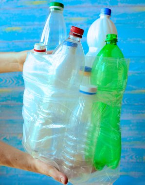Çöpleri ve atıkları ayıklıyorum. Erkek eller mavi arka planda geri dönüşüm için plastik şişelerle dolu bir çanta tutuyor. Plastiği durdur. Ekoloji. Geri dönüşüm konsepti. Sıfır kayıp. Yakın plan.