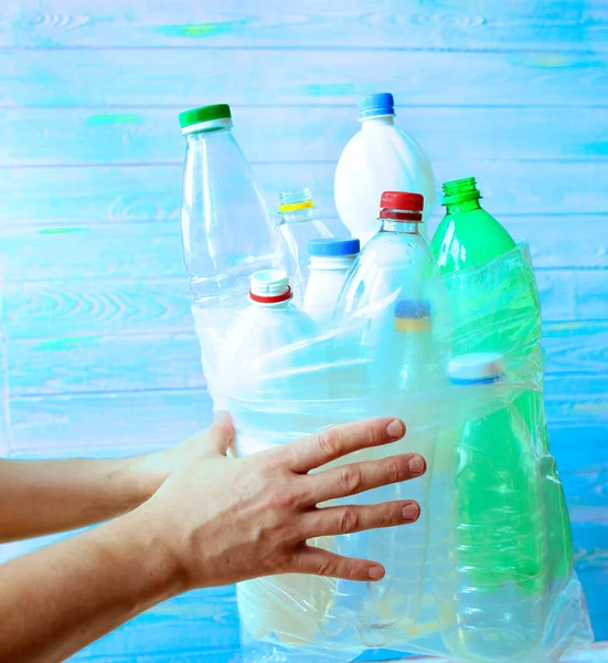 Sorting garbage and waste. A man holds a bag with prepared plastic bottles for recycling on a blue background. Stop plastic. Ecology. Recycling concept. Zero waste. Close-up