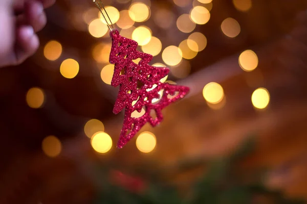 Rode decoratieve kerstboom takken in de hand van de vrouw. Bokeh op de achtergrond. Kerstkaart — Stockfoto