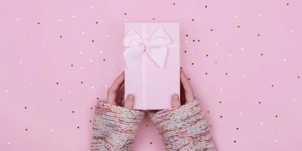 Rózsaszín Ajándék vagy jelen doboz női kézben csillagok konfetti rózsaszín háttérrel. Lapos laikus kompozíció születésnapra, szilveszterre, másolási szakasz — Stock Fotó