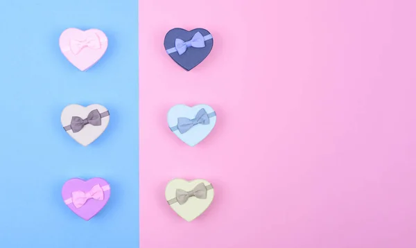 Pequeñas cajas de regalo multicolores corazones sobre fondo azul y rosa, vista superior, espacio de copia — Foto de Stock