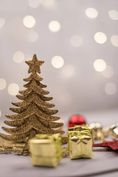 Gold Christmas tree, balls and mini gifts on the background of bokeh lights