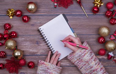 Kadın elleri Noel kontrol listesi yazar, Noel Baba 'ya Noel balosuyla birlikte tahta arka planda mektup yazar. Düz yatıyordu.