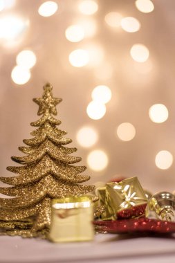 Dekoratif Altın Noel ağacı, balolar ve arka planda küçük hediyeler.