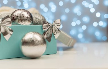 Mavi bokeh ışıklarının arkasında gümüş Noel topları olan mavi kulübe.