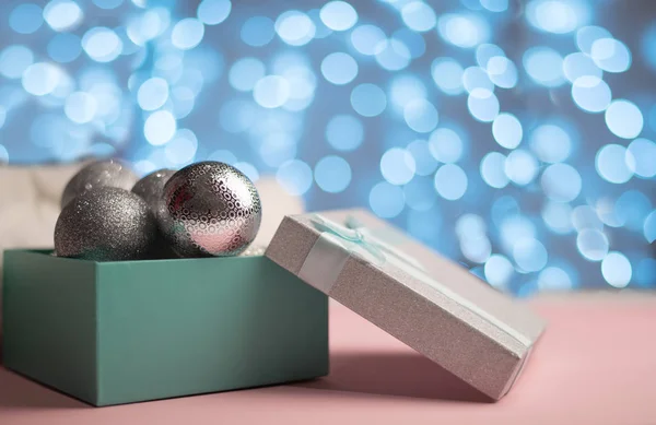 Modrá a stříbrná krabička se stříbrnými vánoční koule na pozadí modré bokeh světla New Yar karty — Stock fotografie