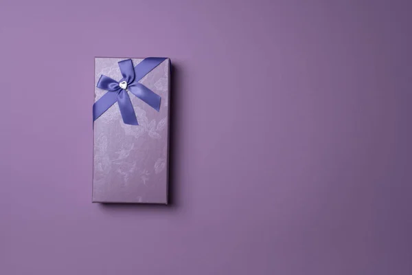 Rectangular purple gift box with bow on purple background, top view — 스톡 사진