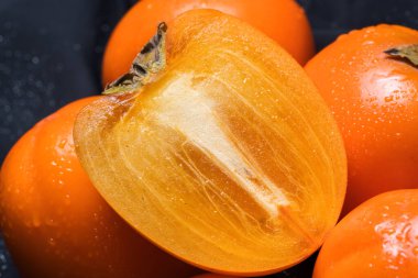 Taze olgun hurma meyvesi, kış meyvesi, güvertede kesilmiş ve siyah arka plan