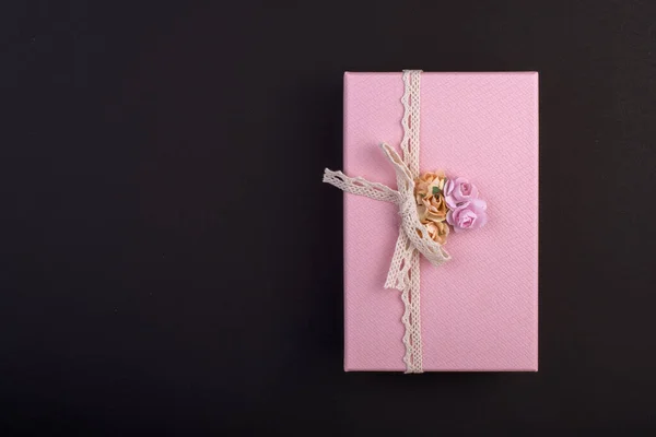 Téglalap alakú rózsaszín ajándékdoboz íjjal és virágokkal fekete alapon, ajándék március 8-án, felülnézet — Stock Fotó