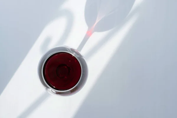 Ein Glas Rotwein auf weißem Hintergrund mit einem Schattenspiel — Stockfoto