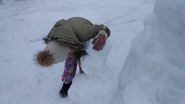 시골에 눈덮인 들판에서 아이가 눈덮인 사람을 만든다 — 비디오
