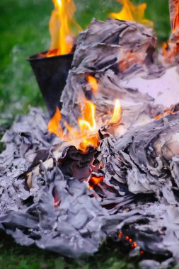 Açık havada yeşil yaz çimlerinde kağıt yanıyor..