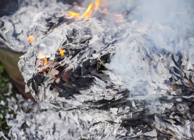 Açık havada yeşil yaz çimlerinde kağıt yanıyor..