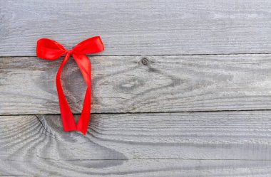Red bright decorative ribbon with bow on old wooden boards background. clipart
