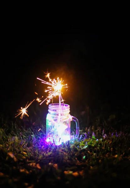 彩色艳丽的花环灯火通明的节日贺卡 在夜间自然背景下的玻璃瓶中点燃 — 图库照片