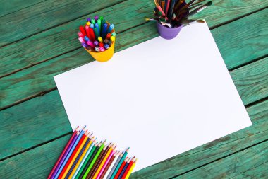 Beyaz kağıt çarşaf ve ahşap arka planda okul malzemeleri..