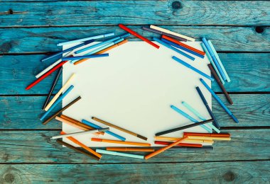 Okul malzemeleri. Okulun tasarım elemanlarına dönüş. Renkli işaretler ve eski ahşap masa zemininde beyaz boş kağıt tabaka.