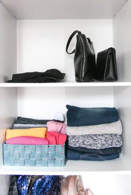 Gardıropta üzerinde kağıt notlar olan farklı kıyafetler. Küçük uzay organizasyonu. Dikey depolama. Kumaş kutularda katlanmış gömlekler..