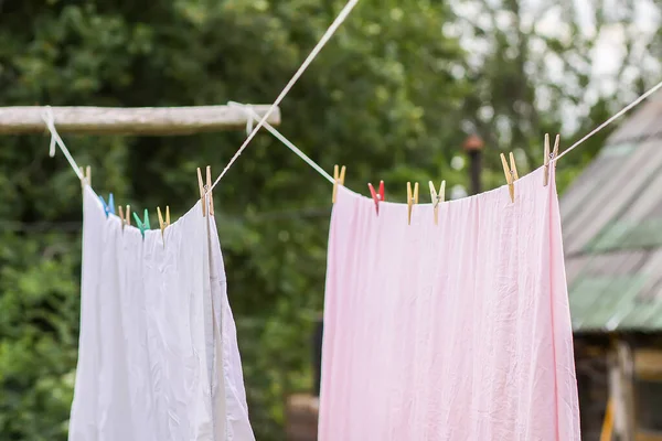 ロープの上に吊るされた新しく洗われたベッドリネン 農村部の庭で衣類乾燥 — ストック写真
