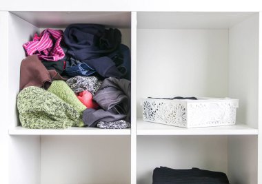 Farklı kıyafetleri olan bir gardırop. Küçük uzay organizasyonu. Düzen ve düzensizliğin karşıtlığı. Dikey depolama.