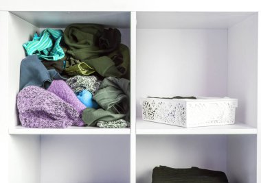 Farklı kıyafetleri olan bir gardırop. Küçük uzay organizasyonu. Düzen ve düzensizliğin karşıtlığı. Dikey depolama.