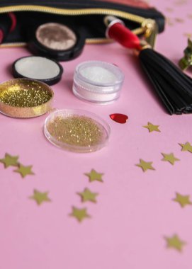 Moda aksesuarlarının parlak kompozisyonu. Parlak pullar, ruj, oje ve diğer eşyalarla dolu kozmetik poşetler. Dekoratif süslemeli yumuşak pastel arka planda nesne. Düz yatış, üst görünüm