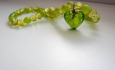 Yeşil boncuklu el yapımı kolye ve gri arka planda Venedik camından yapılmış kalp şeklinde ekleme..