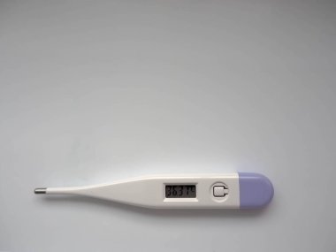 Elektronik termometre beyaz ve mor renk salgın sırasında arka planda normal sıcaklığı gösteriyor.