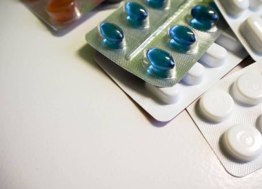 Açık arkaplanda beyaz mavi ve turuncu renkli tablet paketleri