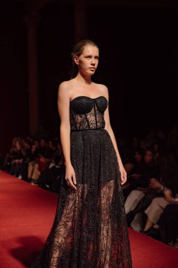 Astrakhan Rusya - 01 Kasım 2019. Caspian Moda Haftası. Bir kadın model kırmızı pistte yürüyor. Moda gösterisi, podyum yürüyüşü.