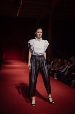 Astrakhan Rusya - 01 Kasım 2019. Caspian Moda Haftası. Bir kadın model kırmızı pistte yürüyor. Moda gösterisi, podyum yürüyüşü.