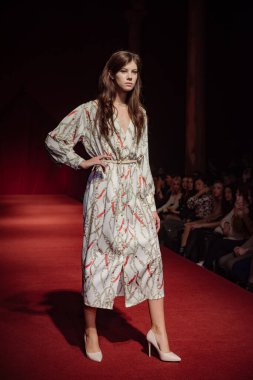 Astrakhan Rusya - 01 Kasım 2019. Caspian Moda Haftası. Bir kadın model kırmızı pistte yürüyor. Moda gösterisi, podyum yürüyüşü.