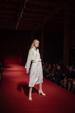 Astrakhan Rusya - 01 Kasım 2019. Caspian Moda Haftası. Bir kadın model kırmızı pistte yürüyor. Moda gösterisi, podyum yürüyüşü.