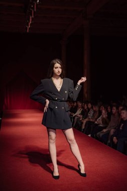 Astrakhan Rusya - 01 Kasım 2019. Caspian Moda Haftası. Bir kadın model kırmızı pistte yürüyor. Moda gösterisi, podyum yürüyüşü.