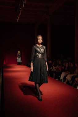 Astrakhan Rusya - 01 Kasım 2019. Caspian Moda Haftası. Bir kadın model kırmızı pistte yürüyor. Moda gösterisi, podyum yürüyüşü.