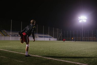 Futbolcu gece maçından önce sahada ısınma egzersizleri yapıyor.