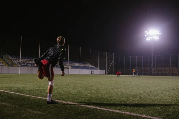 Giocatore di calcio che fa esercizi di riscaldamento sul campo prima della partita di notte — Foto Stock