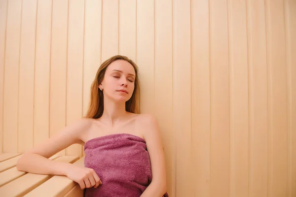 Beautiful woman relaxing in sauna and staying healthy