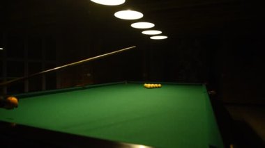 Beyaz gömlekli genç adam bilardo oynuyor..