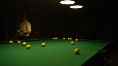 Beyaz gömlekli genç adam bilardo oynuyor..